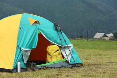 Photo of Camping tent and tourist stuff on green grass in mountains