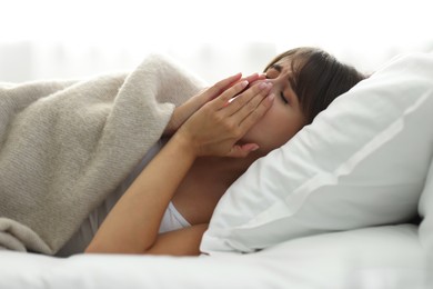 Woman suffering from sinusitis in bed indoors