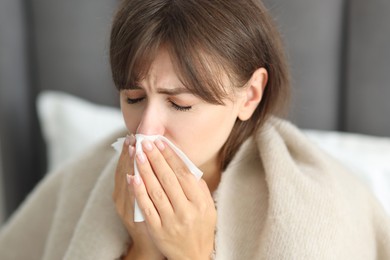 Woman wrapped in blanket suffering from sinusitis at home