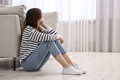 Photo of Loneliness concept. Sad teenage girl on floor at home, space for text