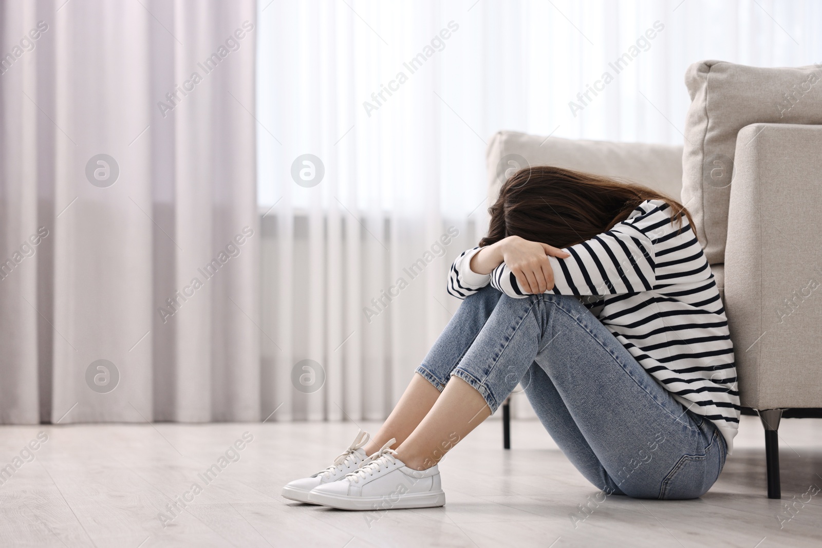 Photo of Loneliness concept. Sad teenage girl on floor at home, space for text