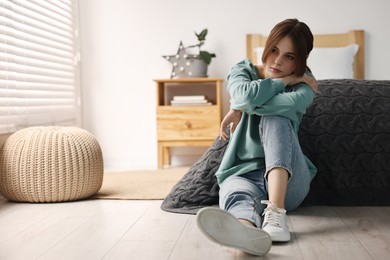 Photo of Loneliness concept. Sad teenage girl on floor at home, space for text