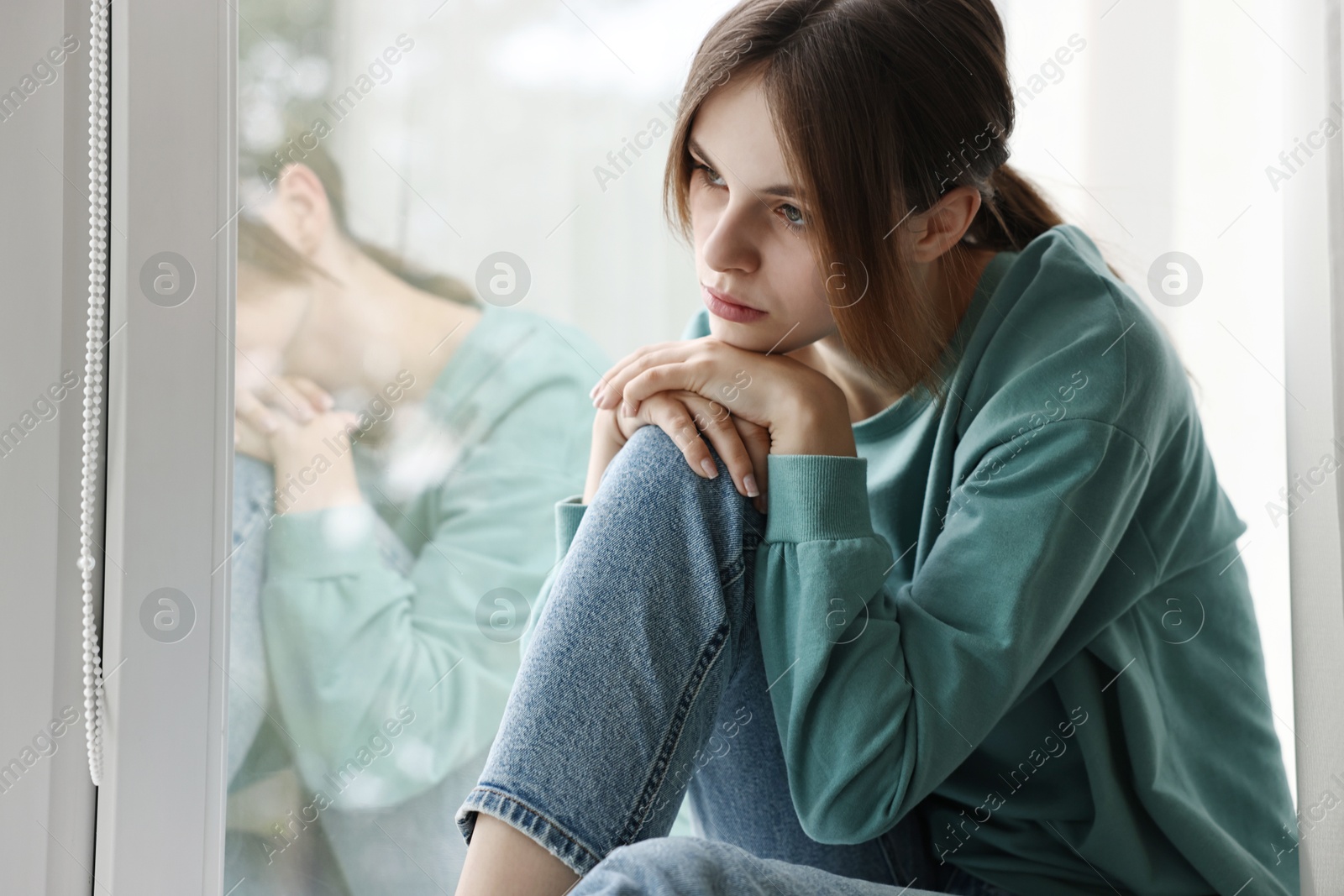 Photo of Loneliness concept. Sad teenage girl near window at home