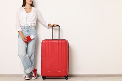 Photo of Woman with suitcase, passport and ticket indoors, closeup. Space for text