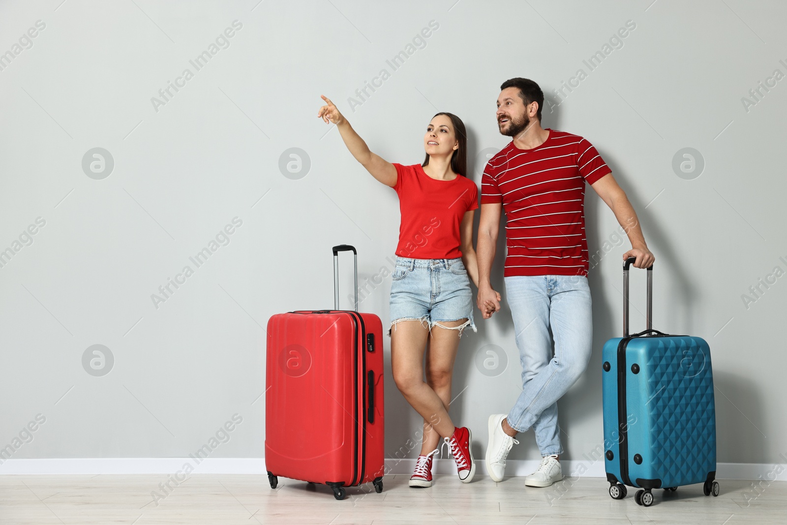 Photo of Happy couple with suitcases indoors, space for text