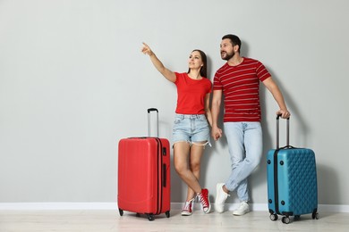 Photo of Happy couple with suitcases indoors, space for text