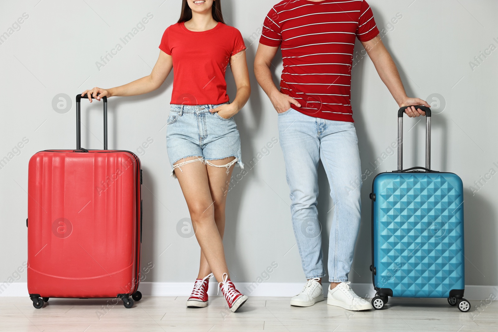 Photo of Man and woman with suitcases near light gray wall indoors, closeup