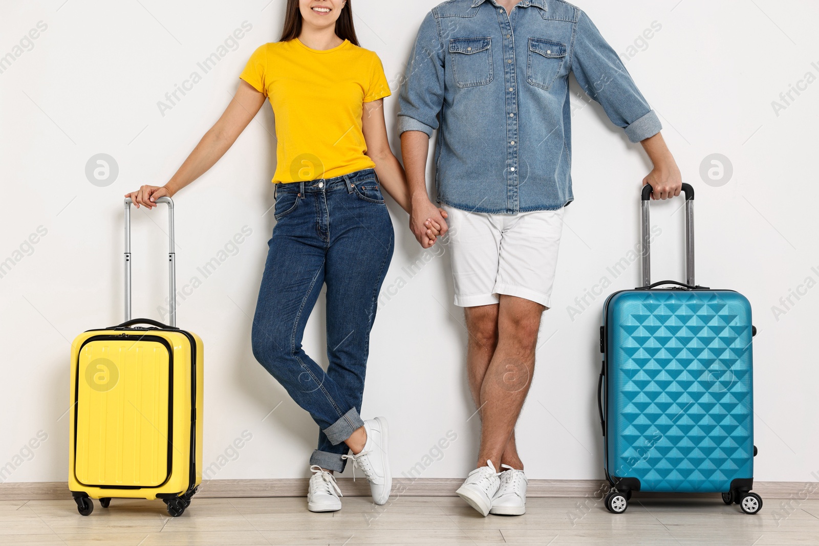 Photo of Man and woman with suitcases near light wall indoors, closeup