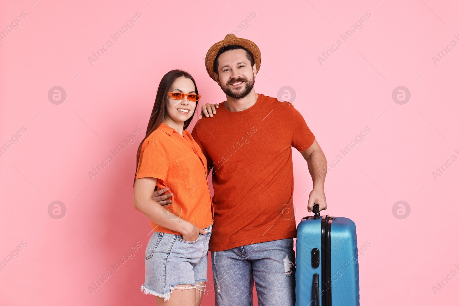 Photo of Happy woman and man with suitcase on pink background