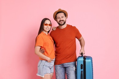 Happy woman and man with suitcase on pink background