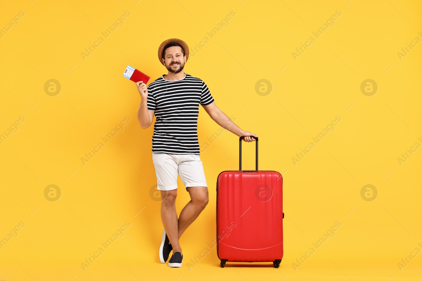 Photo of Happy man with suitcase, passport and ticket on orange background