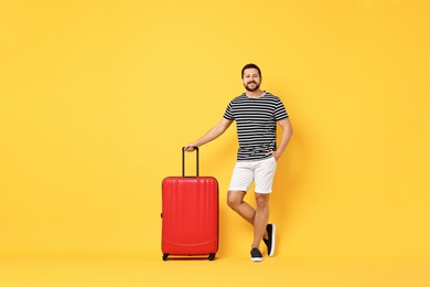 Photo of Happy man with suitcase on orange background