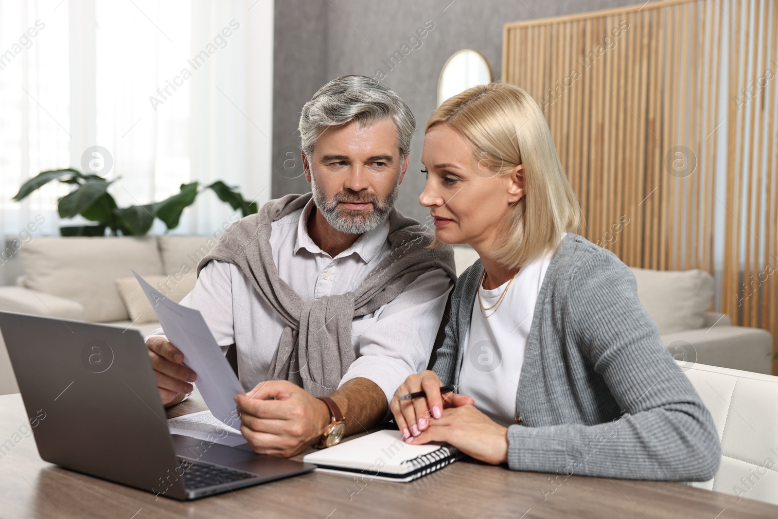 Photo of Couple planning pension budget at table indoors