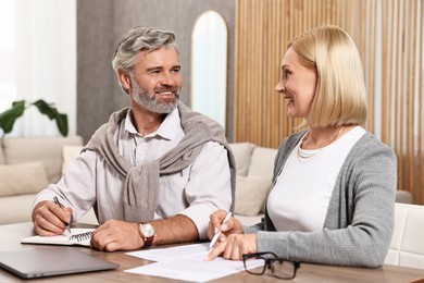 Photo of Couple planning pension budget at table indoors