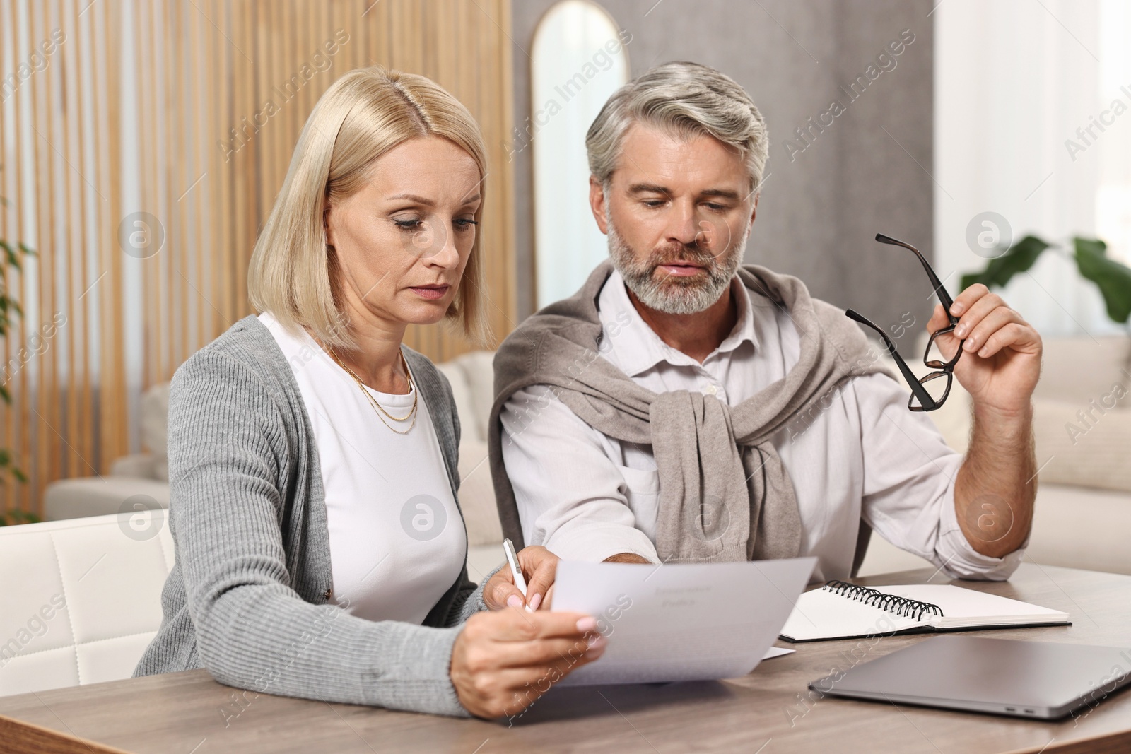 Photo of Couple planning pension budget at table indoors