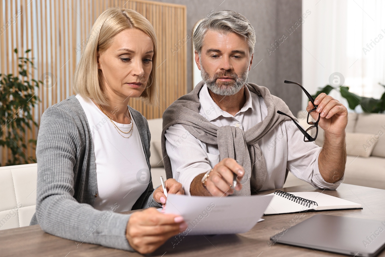 Photo of Couple planning pension budget at table indoors