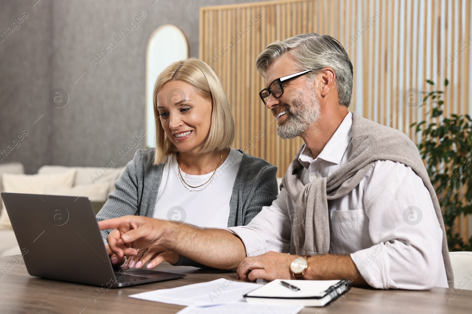 Photo of Couple planning pension budget at table indoors