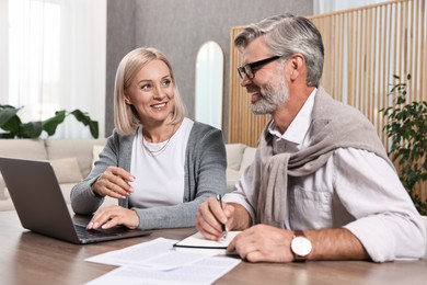 Photo of Couple planning pension budget at table indoors