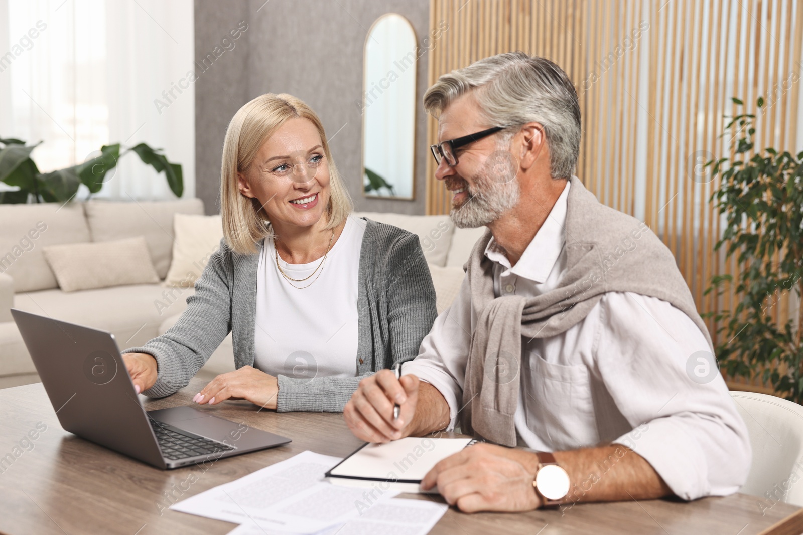 Photo of Couple planning pension budget at table indoors