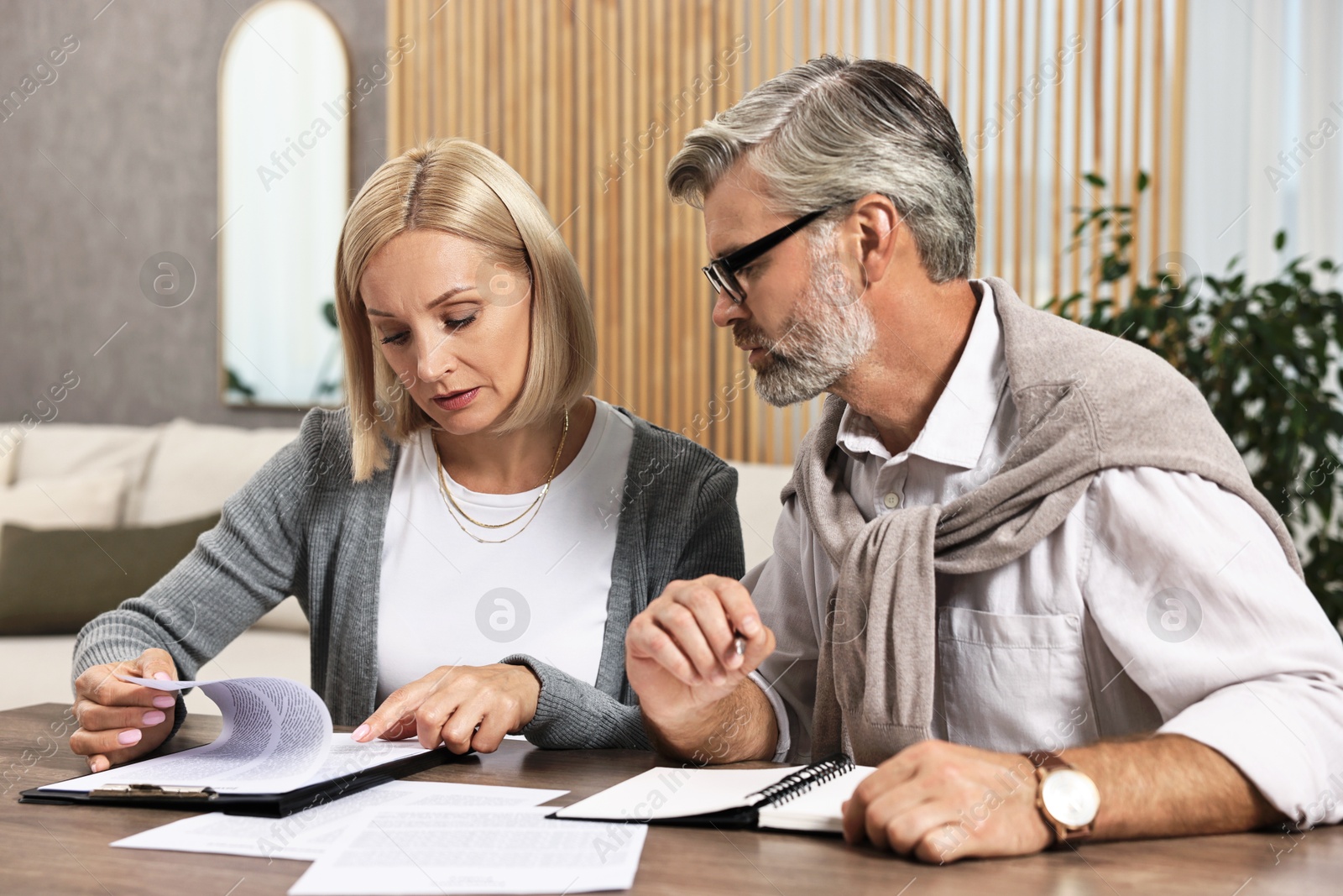 Photo of Couple planning pension budget at table indoors