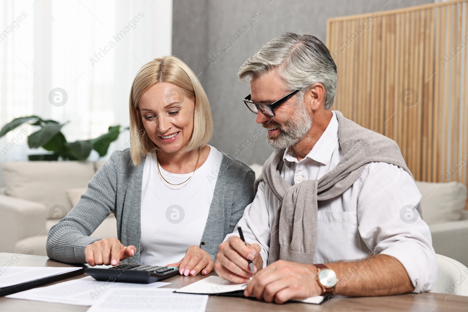 Photo of Couple planning pension budget at table indoors