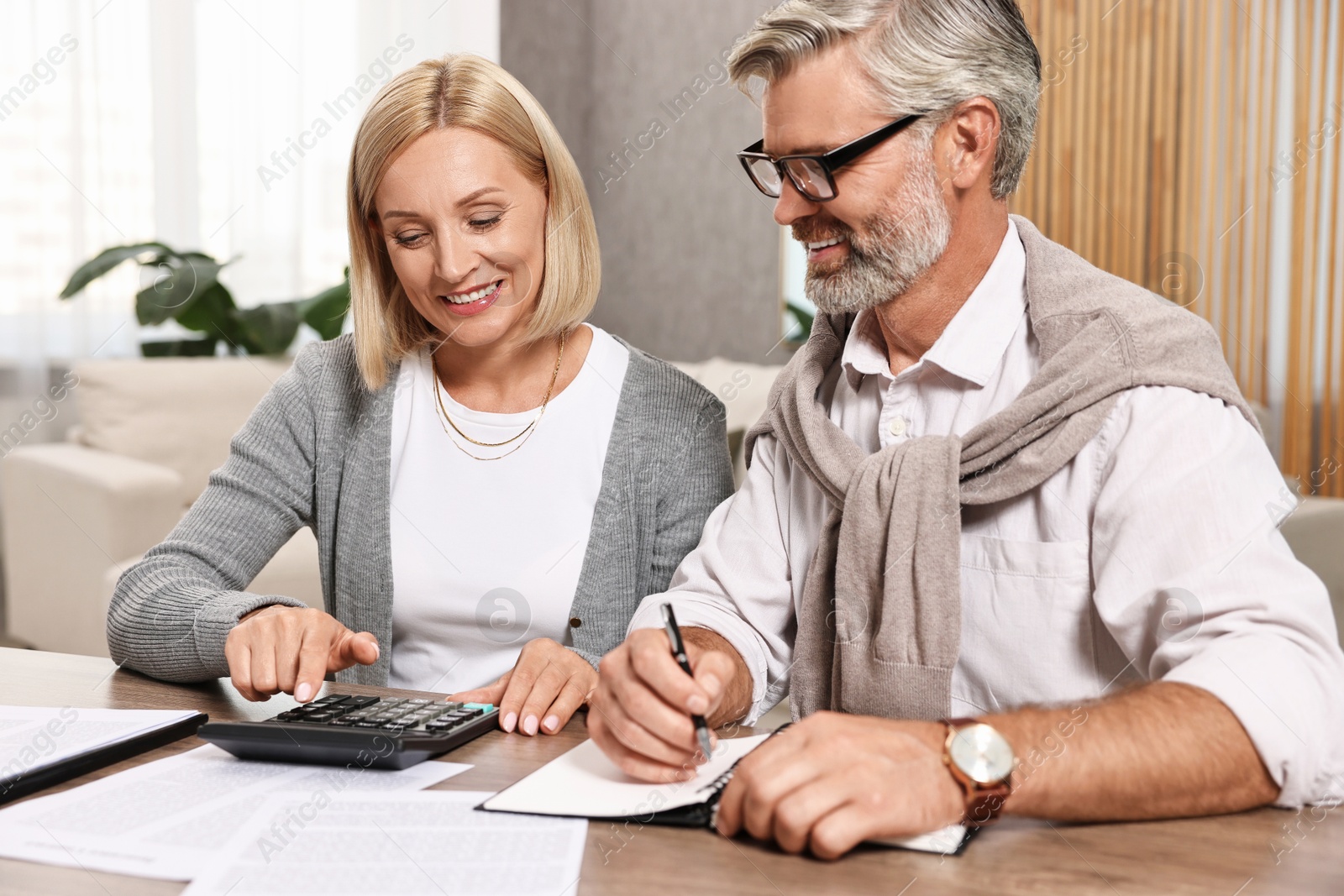 Photo of Couple planning pension budget at table indoors