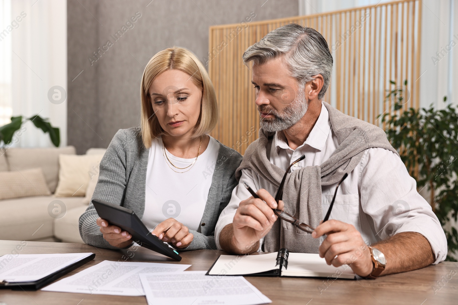 Photo of Couple planning pension budget at table indoors