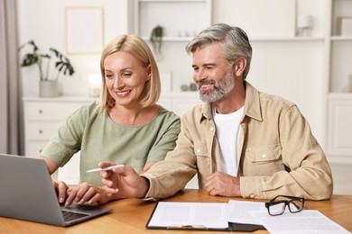 Photo of Couple planning pension budget at table indoors