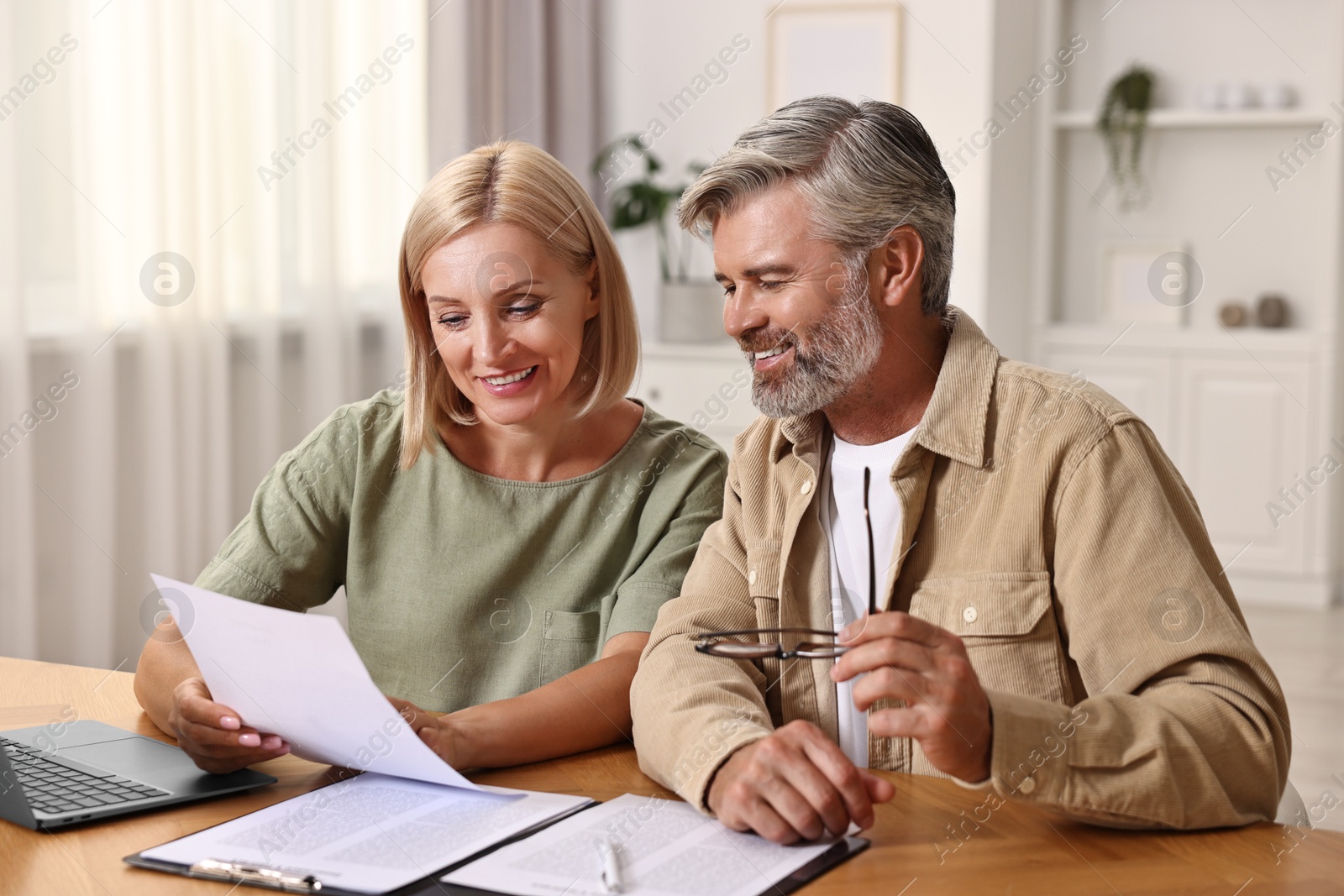 Photo of Couple planning pension budget at table indoors