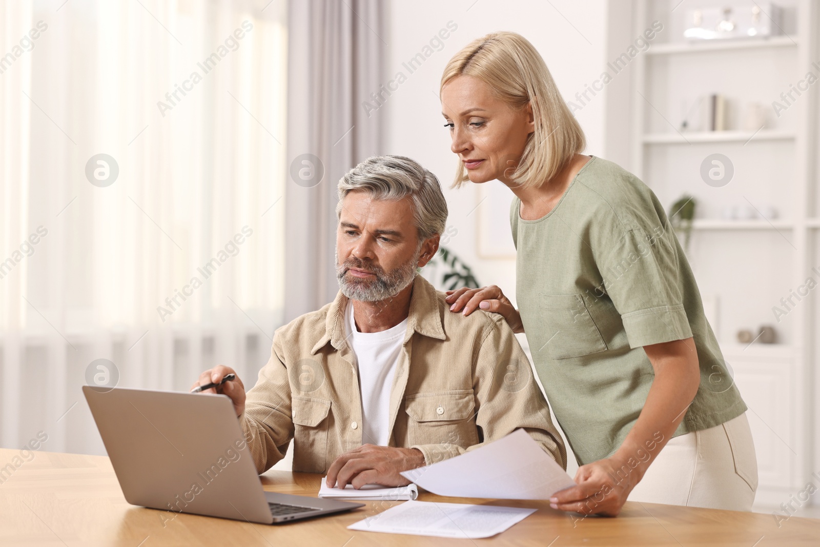 Photo of Couple planning pension budget at table indoors