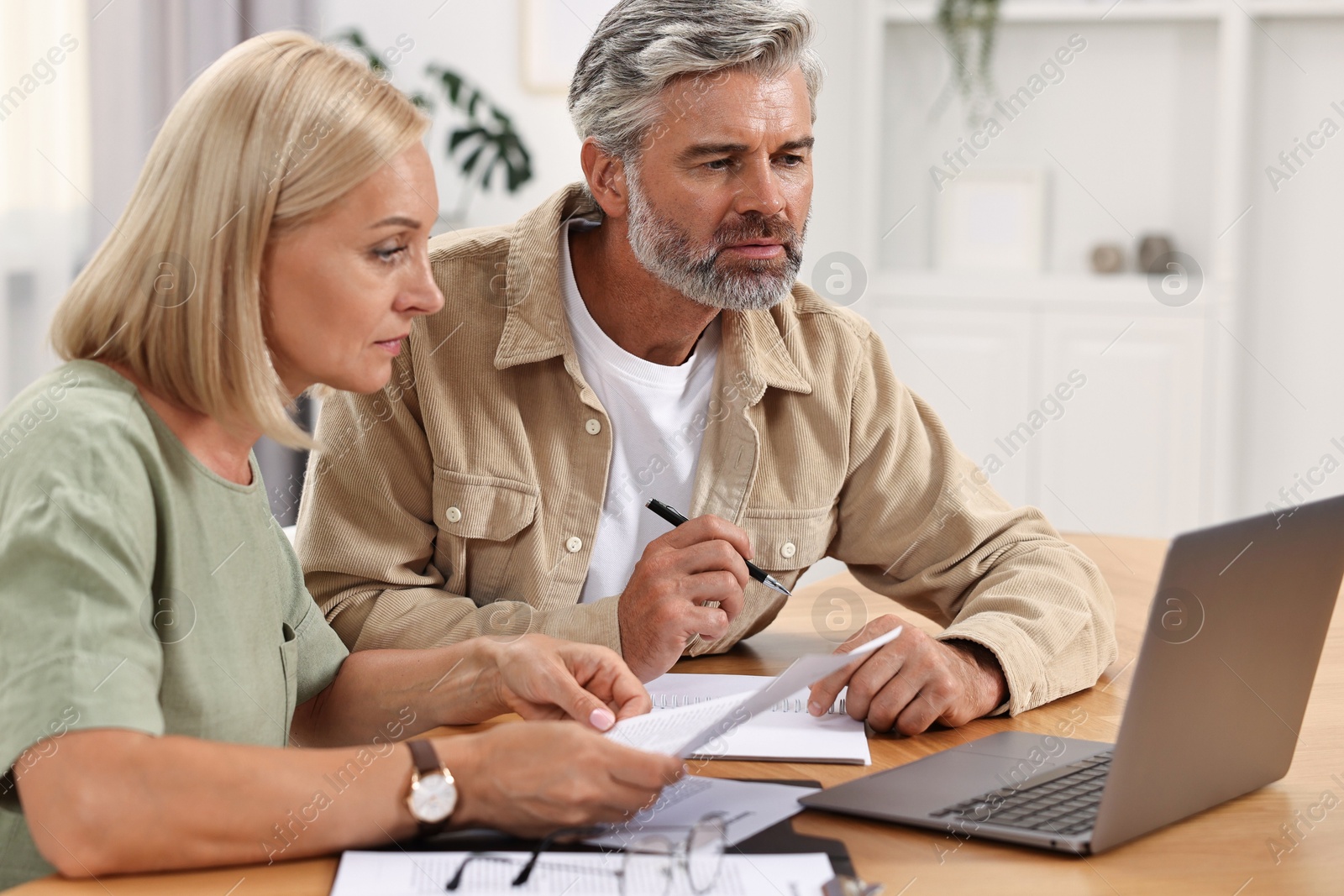 Photo of Couple planning pension budget at table indoors