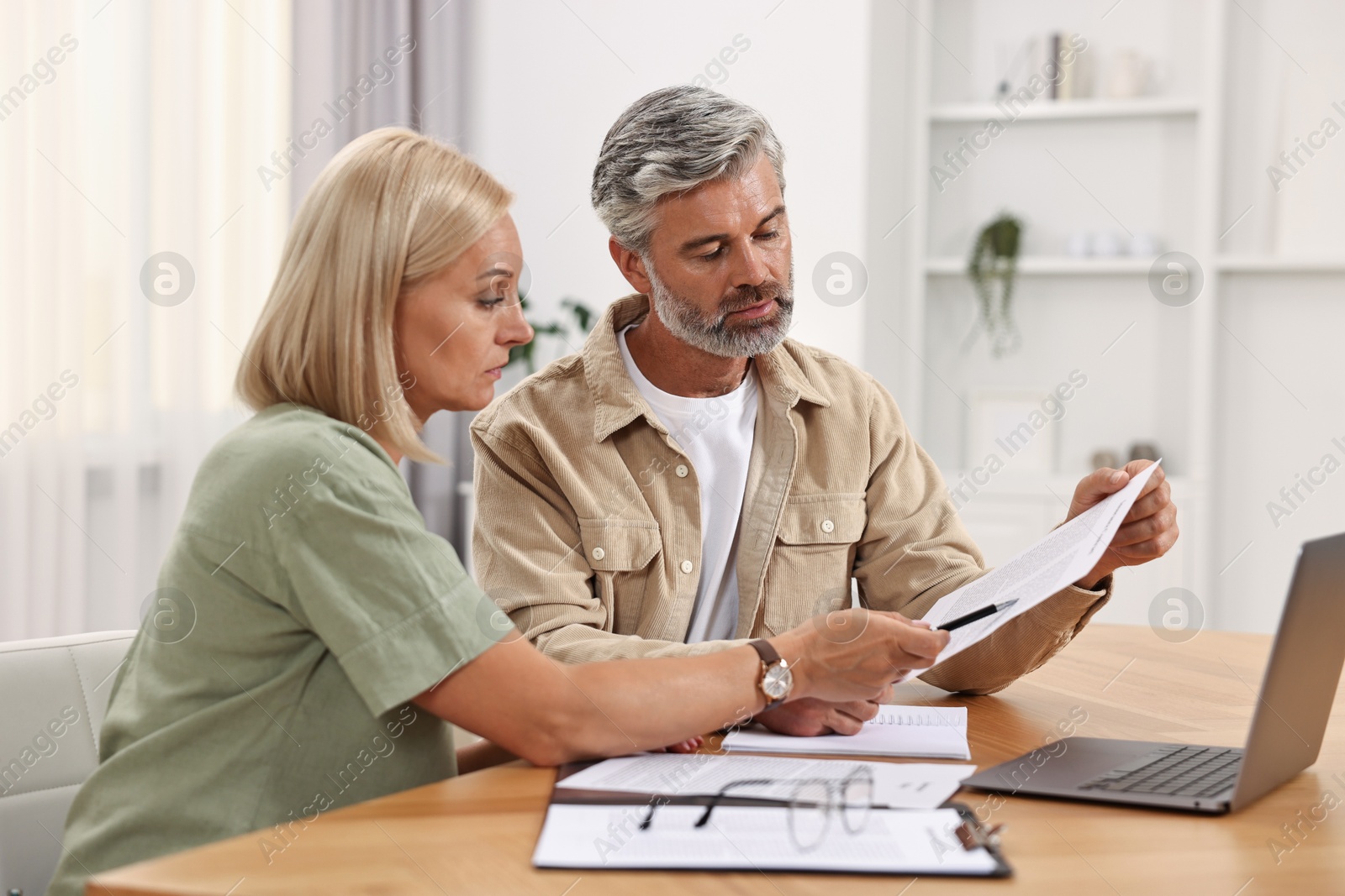 Photo of Couple planning pension budget at table indoors