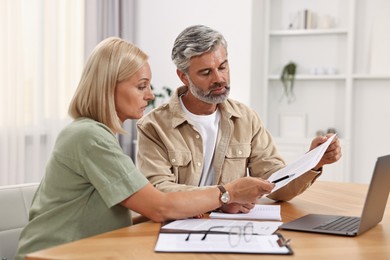 Photo of Couple planning pension budget at table indoors