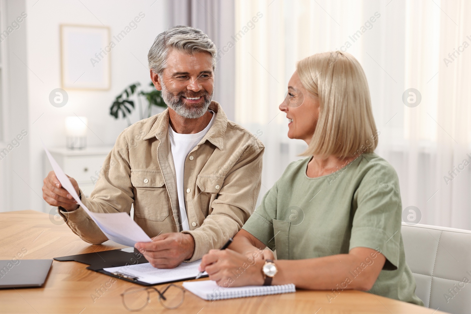 Photo of Couple planning pension budget at table indoors