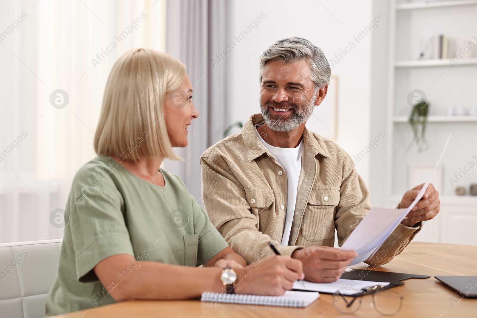 Photo of Couple planning pension budget at table indoors