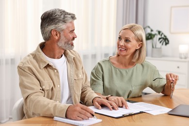 Photo of Couple planning pension budget at table indoors