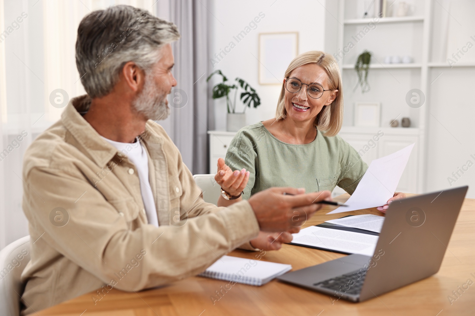 Photo of Pension savings. Couple planning budget at table indoors