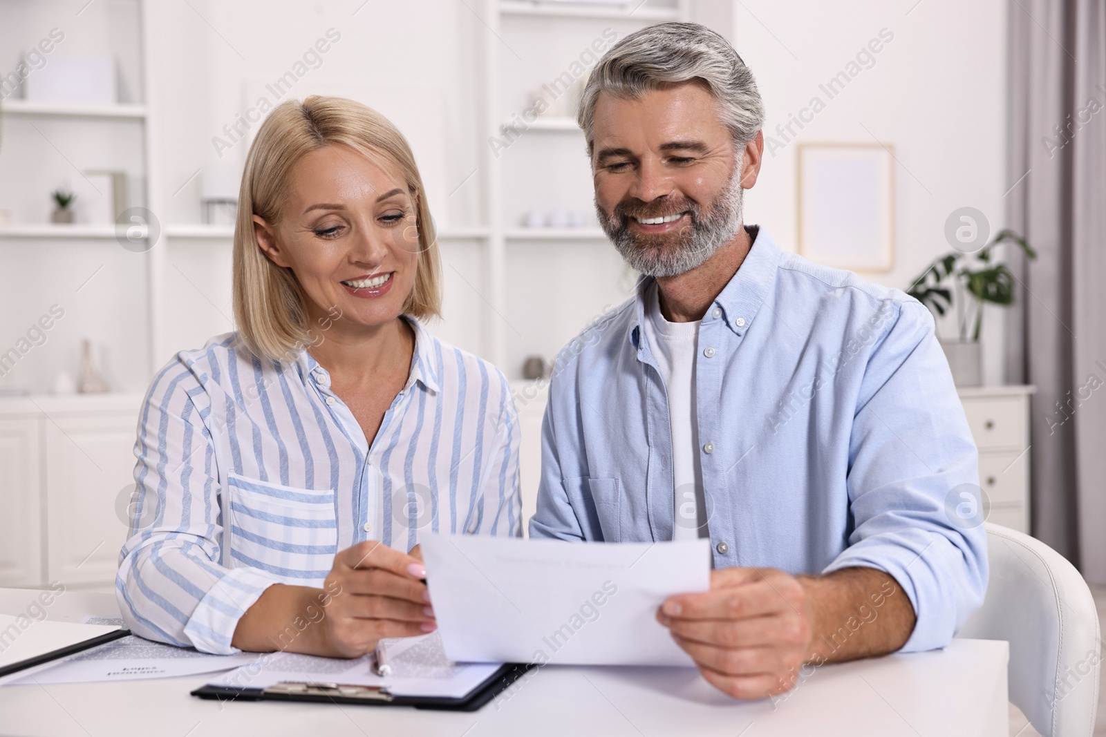 Photo of Pension savings. Couple planning budget at table indoors