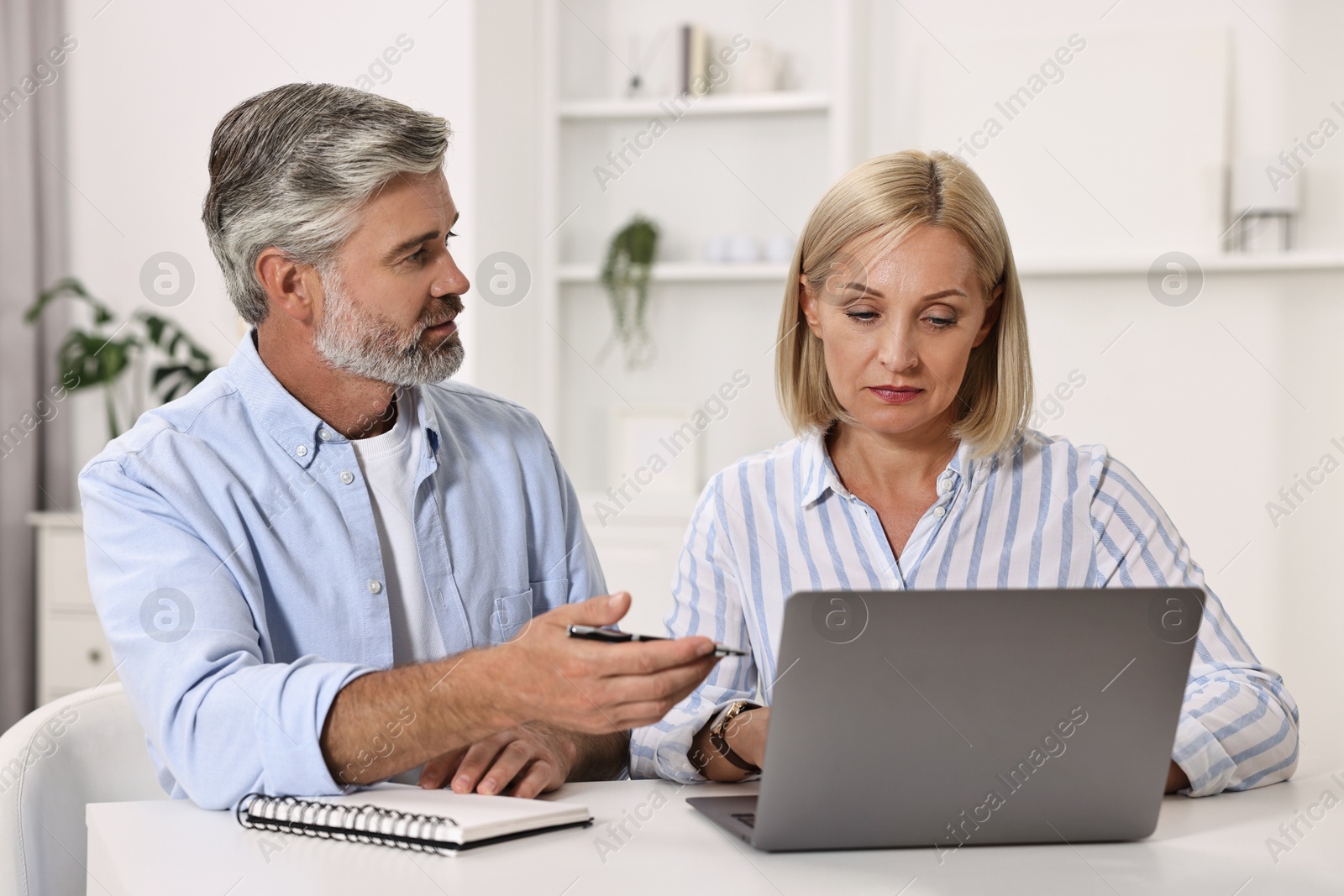 Photo of Pension savings. Couple planning budget at table indoors