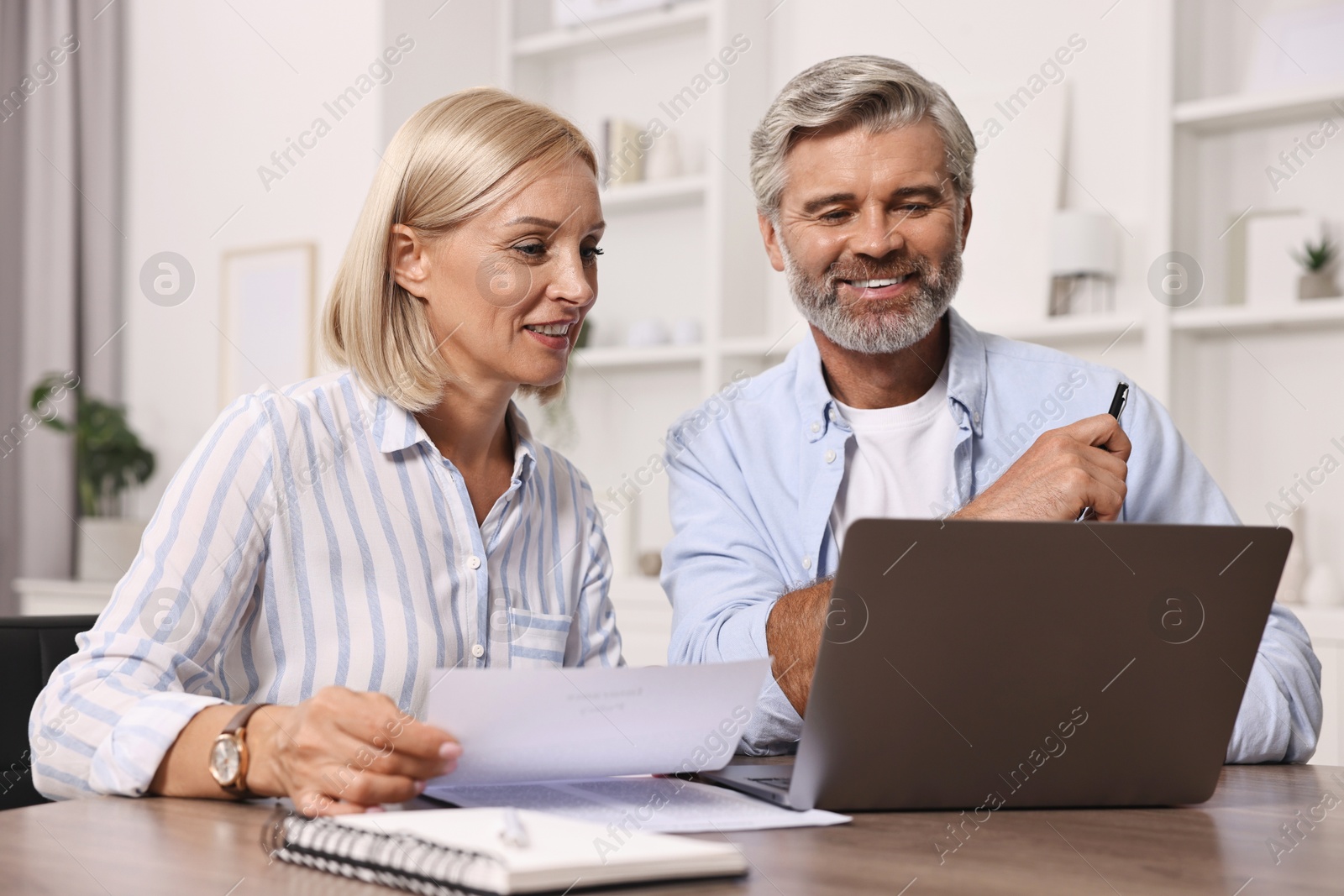 Photo of Pension savings. Couple planning budget at table indoors