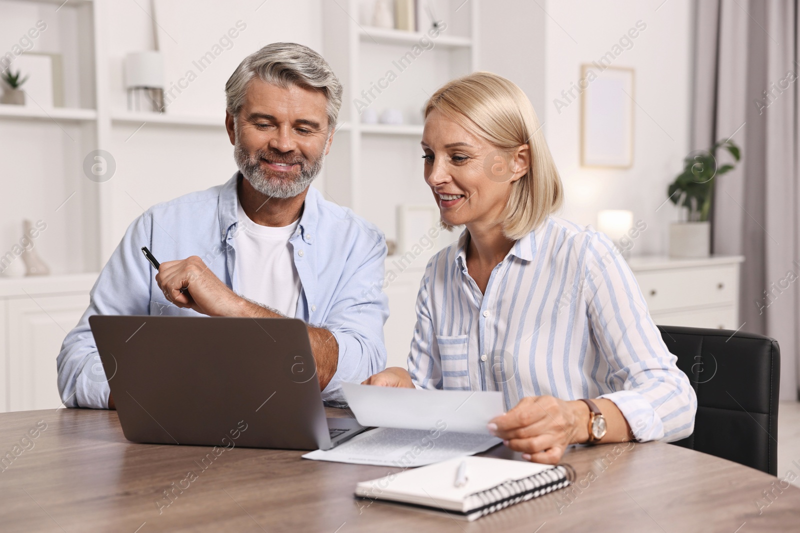 Photo of Pension savings. Couple planning budget at table indoors