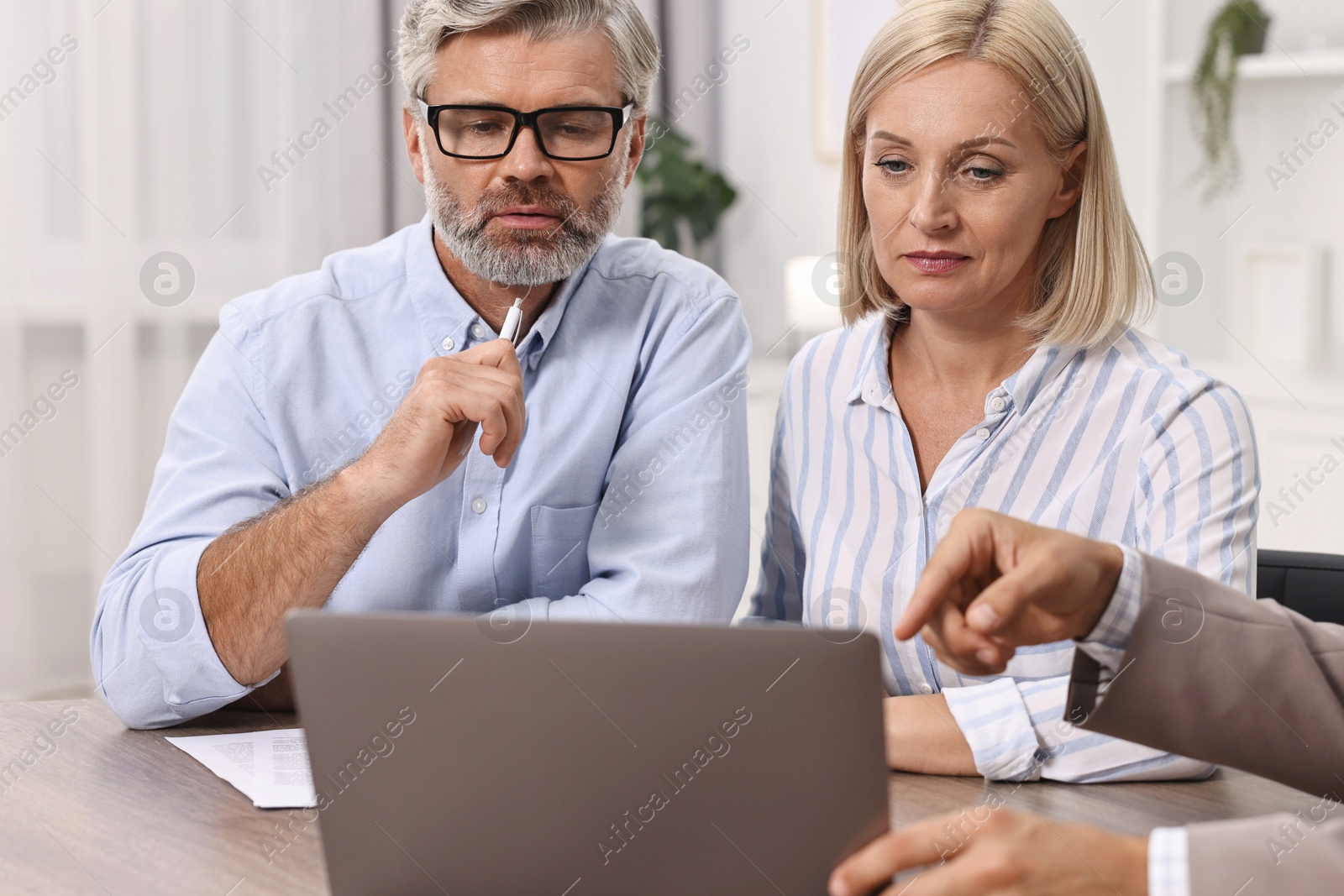 Photo of Pension plan. Couple consulting with insurance agent at table indoors