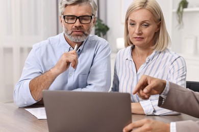 Photo of Pension plan. Couple consulting with insurance agent at table indoors