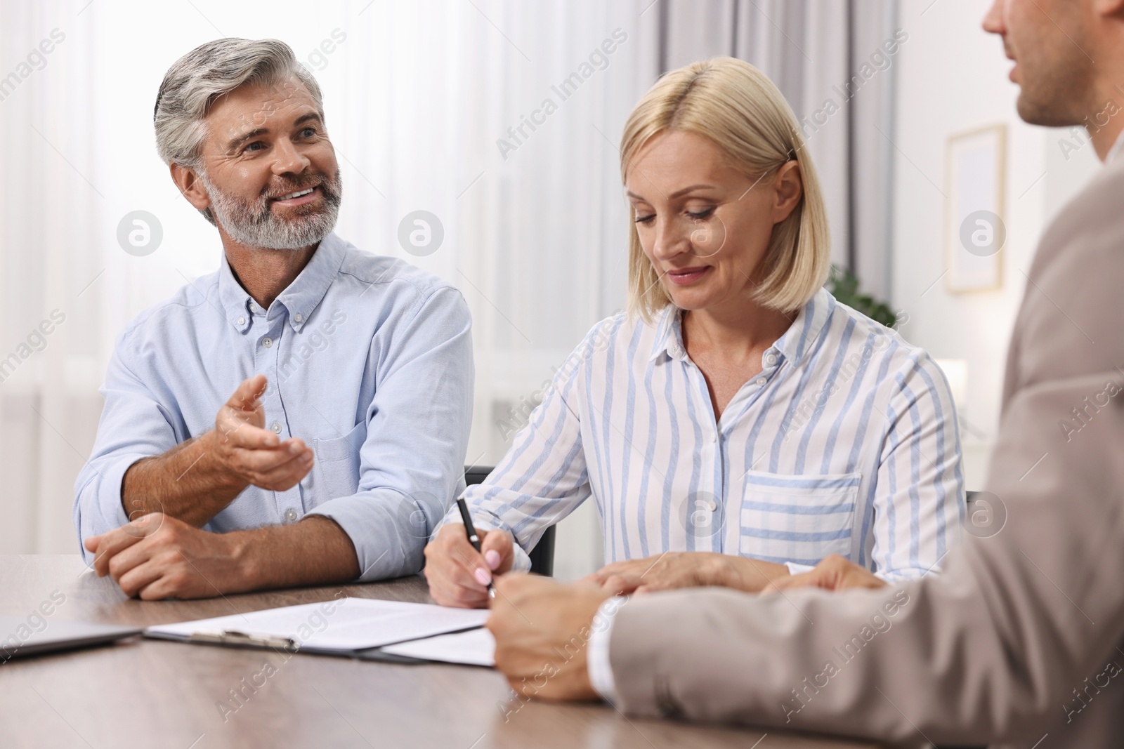 Photo of Pension plan. Couple consulting with insurance agent at table indoors