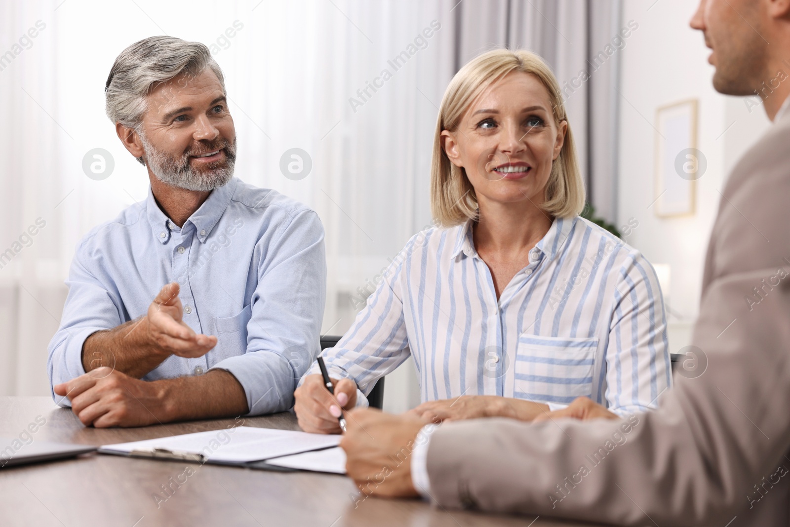 Photo of Pension plan. Couple consulting with insurance agent at table indoors