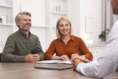 Photo of Pension plan. Couple consulting with insurance agent at table indoors