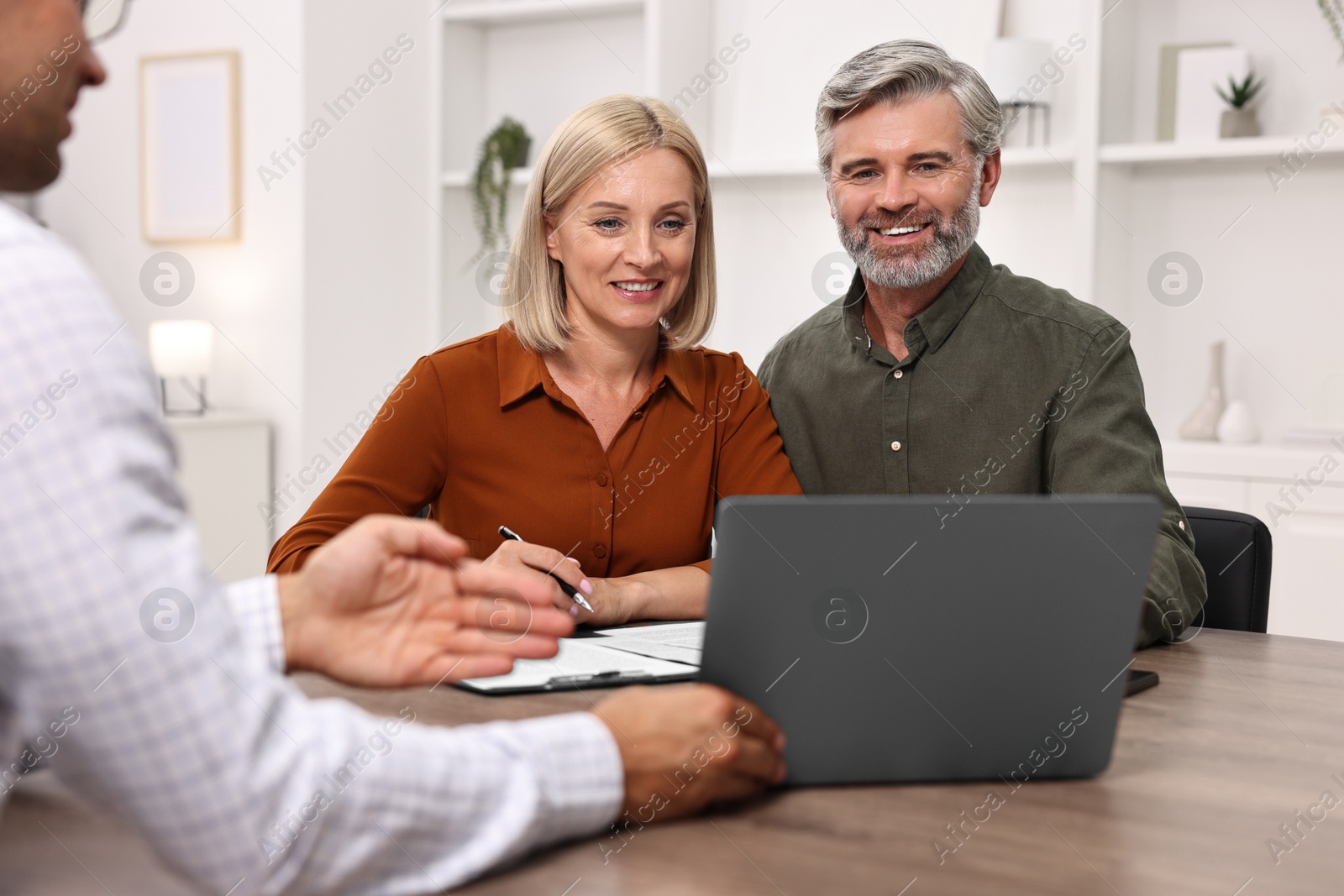 Photo of Pension plan. Couple consulting with insurance agent at table indoors