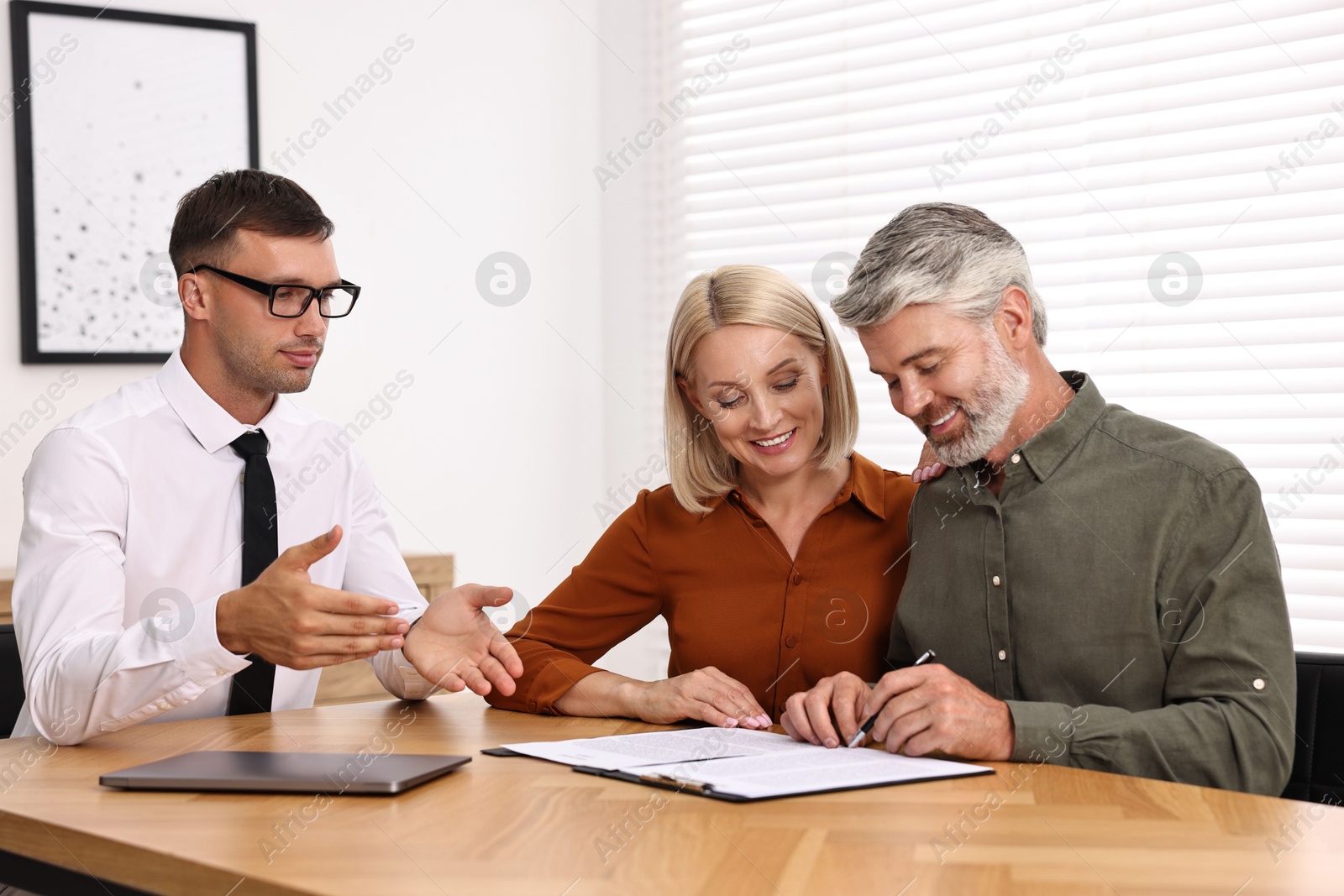 Photo of Pension plan. Couple consulting with insurance agent at table indoors