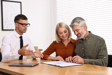 Pension plan. Couple consulting with insurance agent at table indoors