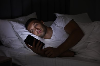 Bad habit. Man using smartphone in bed at night